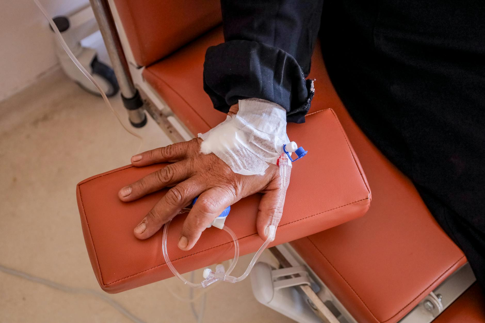 Zbliżenie dłoni pacjenta z wenflonem podczas zabiegu w szpitalu