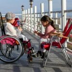 Dziewczynki na tarasie, jedna na wózku, bawią się w słoneczny dzień