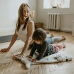 Mama ćwicząca jogę z dzieckiem w słonecznym salonie podczas domowej rehabilitacj