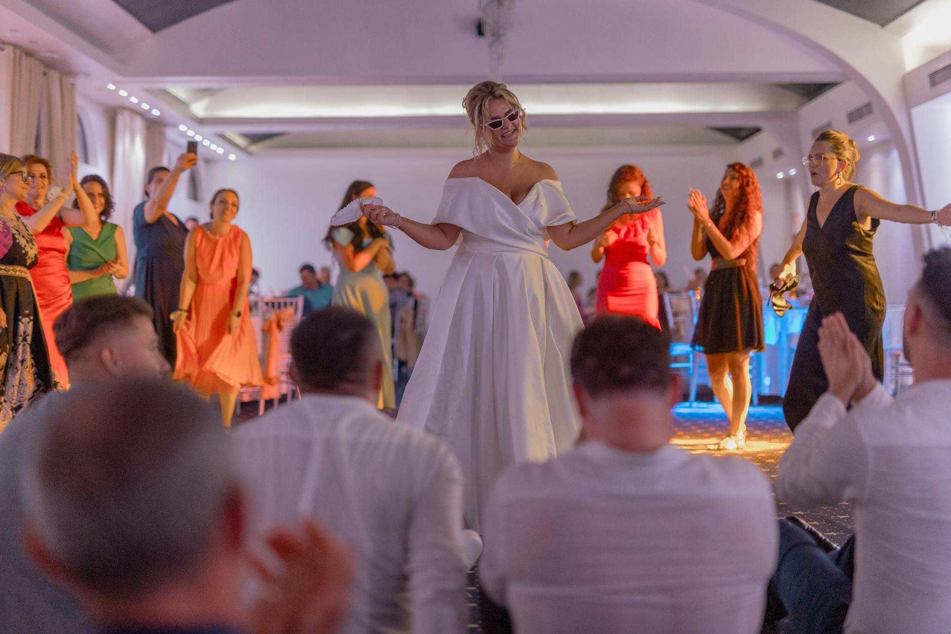 Panna młoda tańczy z gośćmi na eleganckim weselu w sali weselnej