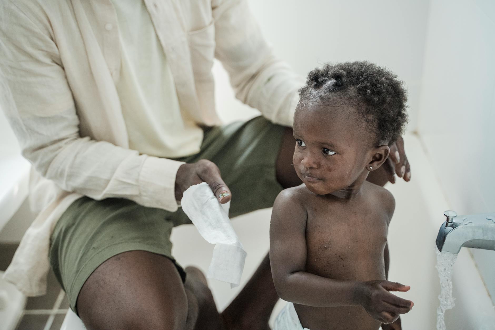 Tata delikatnie kąpie niemowlę w wannie podczas domowej hydroterapii