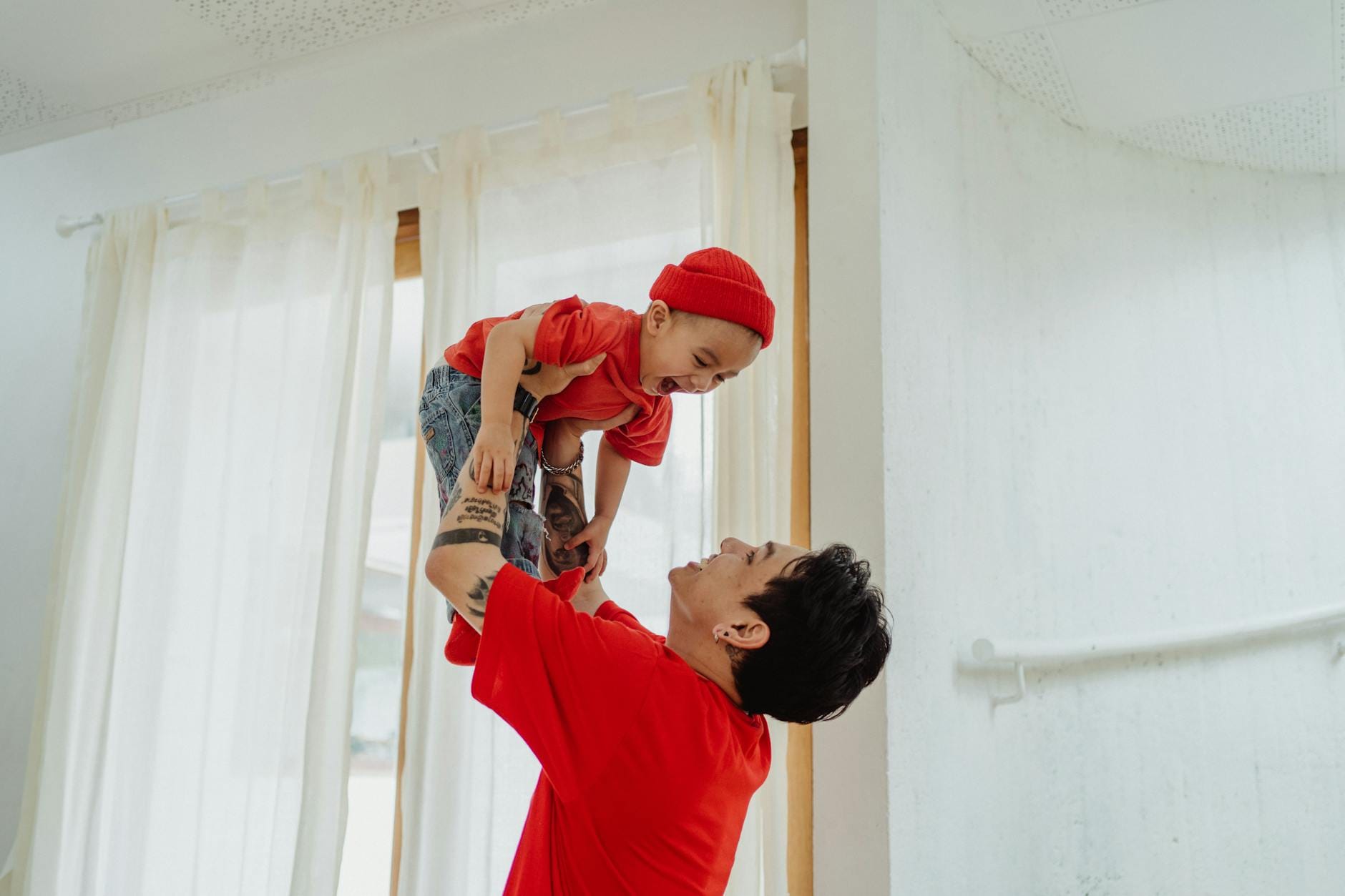 Uśmiechnięty rodzic bawi się z dzieckiem w jasnym pokoju