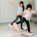 Zabawy na równowagę w salonie: pomysły bez specjalistycznego sprzętu Dwoje dzieci ćwiczy równowagę na drewnianych deskach w salonie