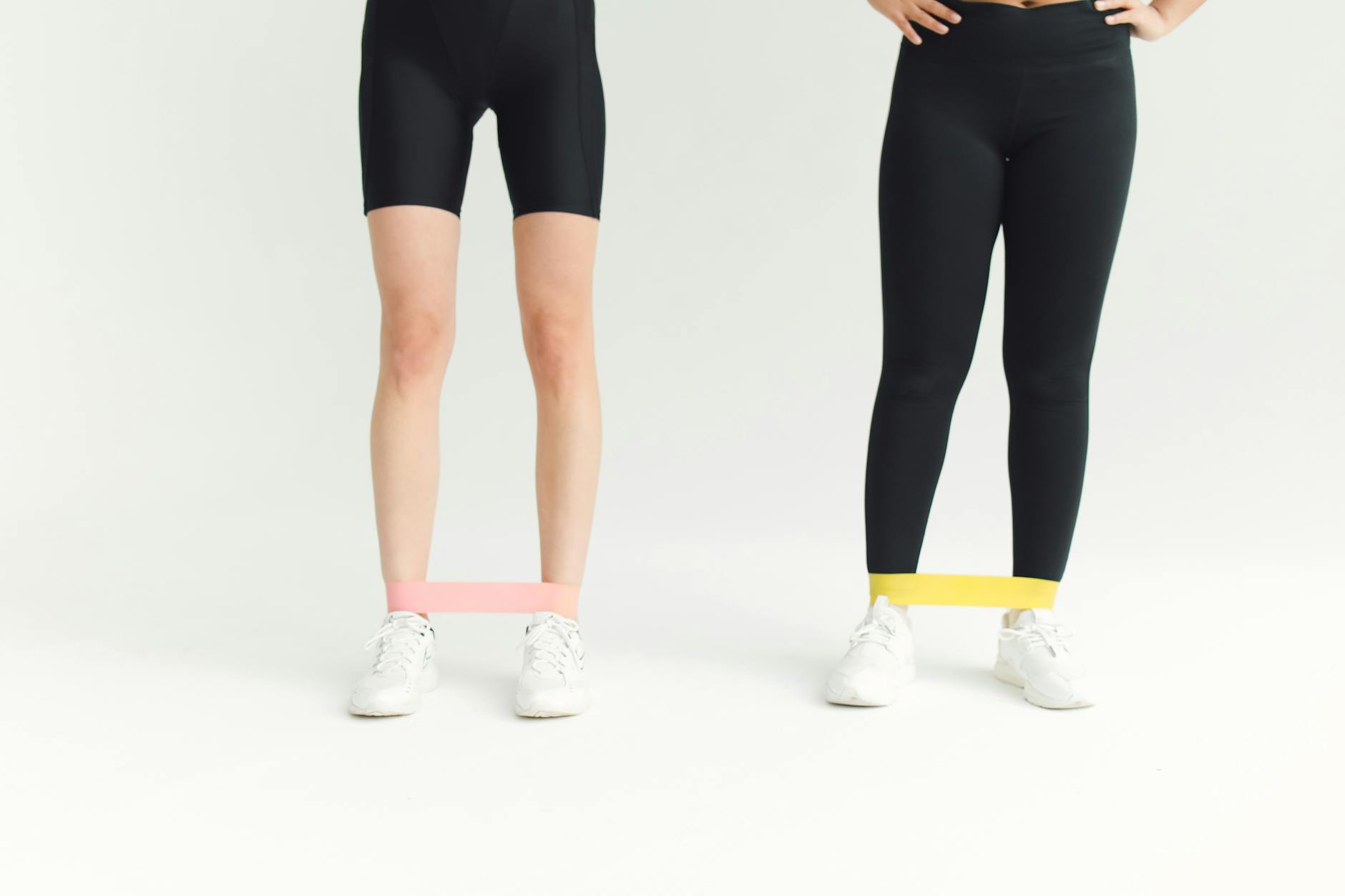 Kobiety w stroju sportowym ćwiczą z gumami oporowymi w domu