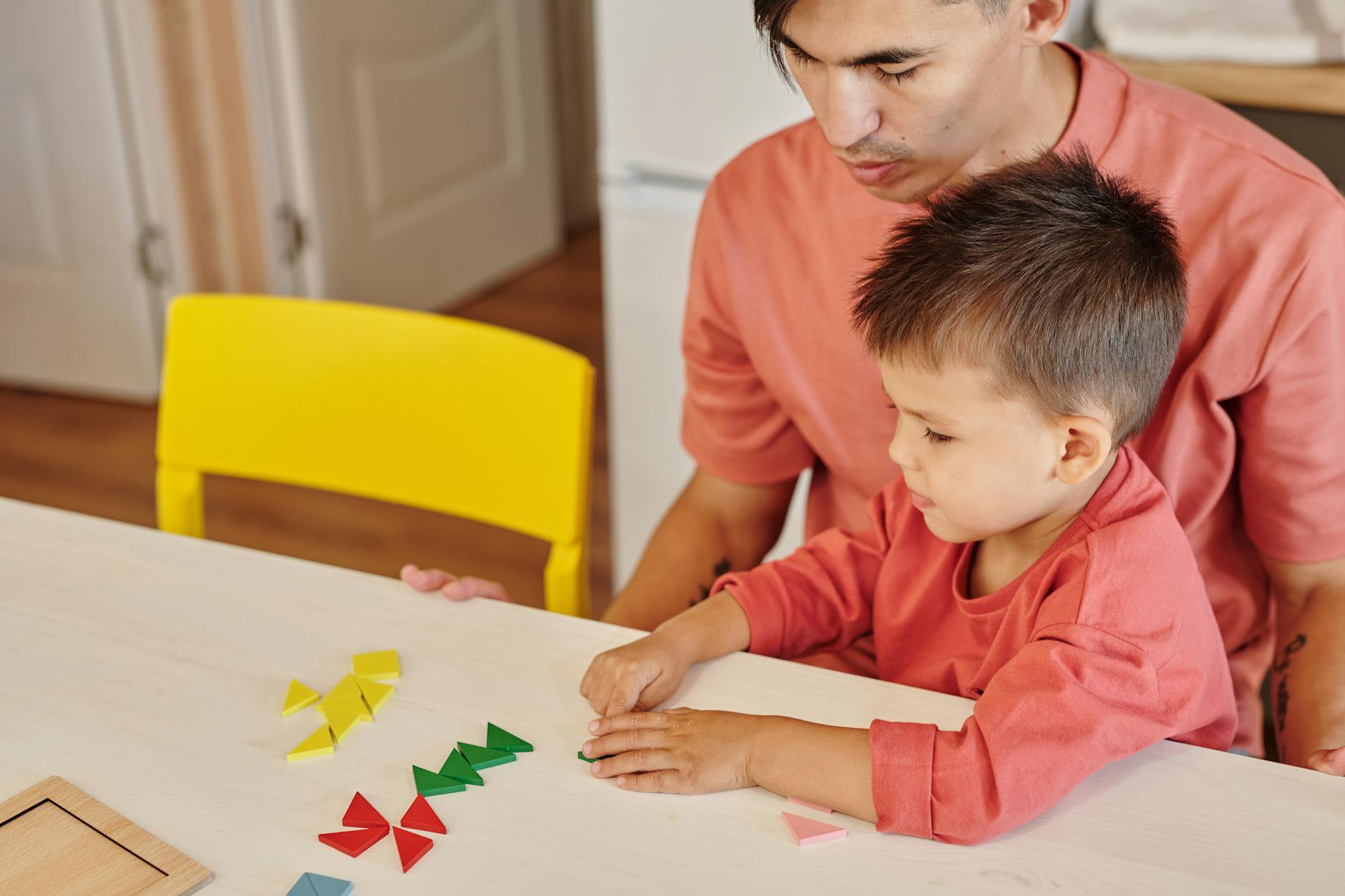 Tata i syn bawią się w domu kolorowymi edukacyjnymi kształtami