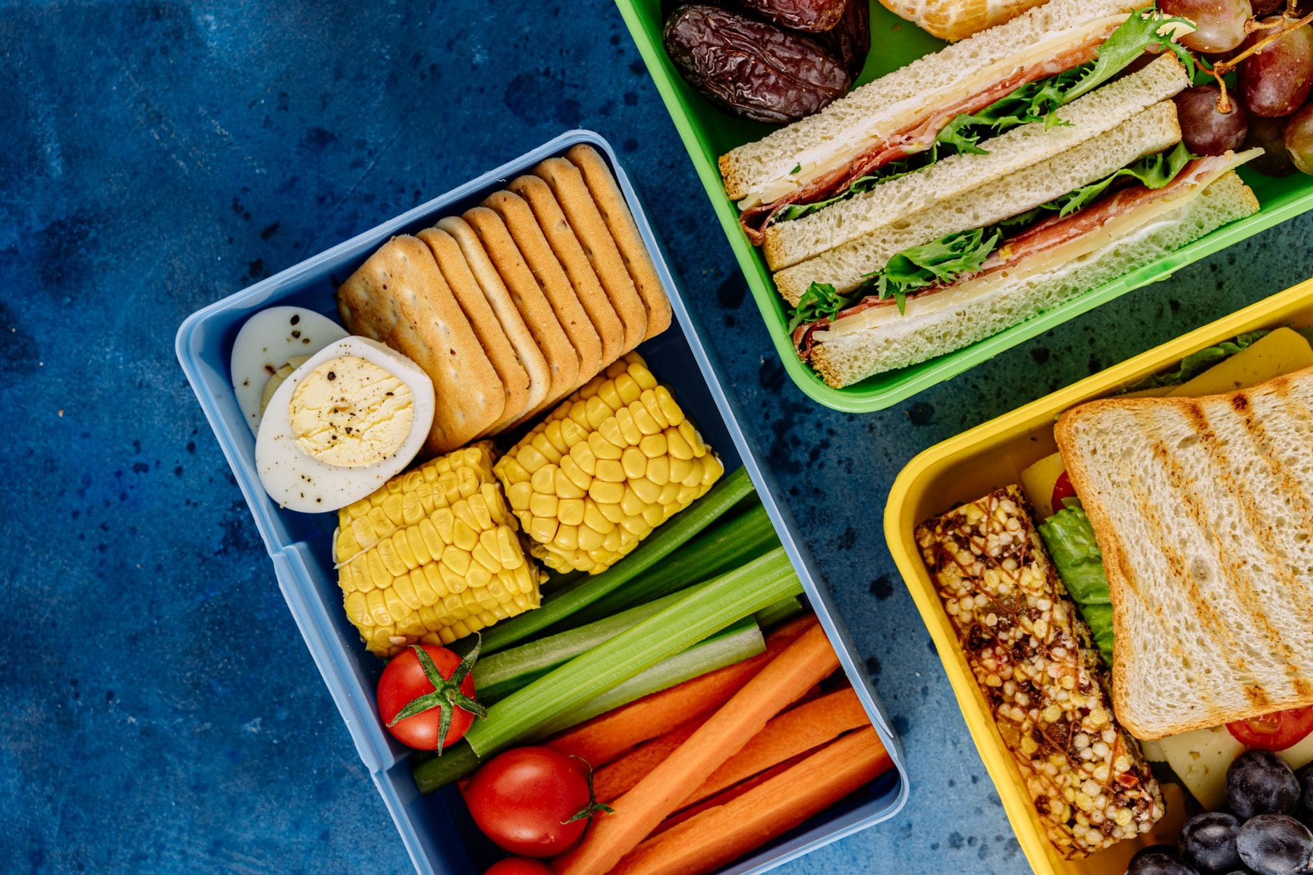 Kolorowe lunchboksy z kanapkami, warzywami i zdrowymi przekąskami