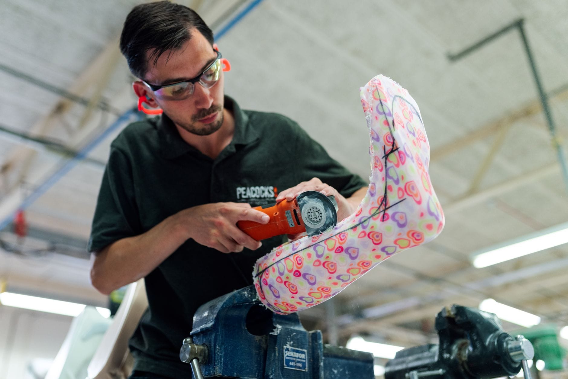 Technik w pracowni szlifuje kolorową ortezę skokowo-stopową dla dziecka