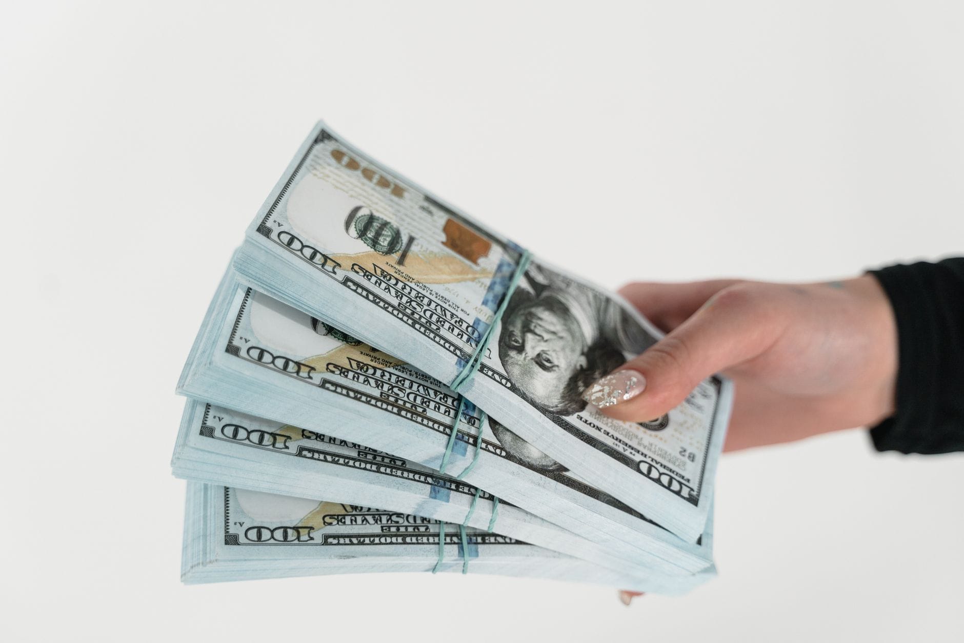Dłoń trzymająca plik banknotów dolarowych na białym tle
